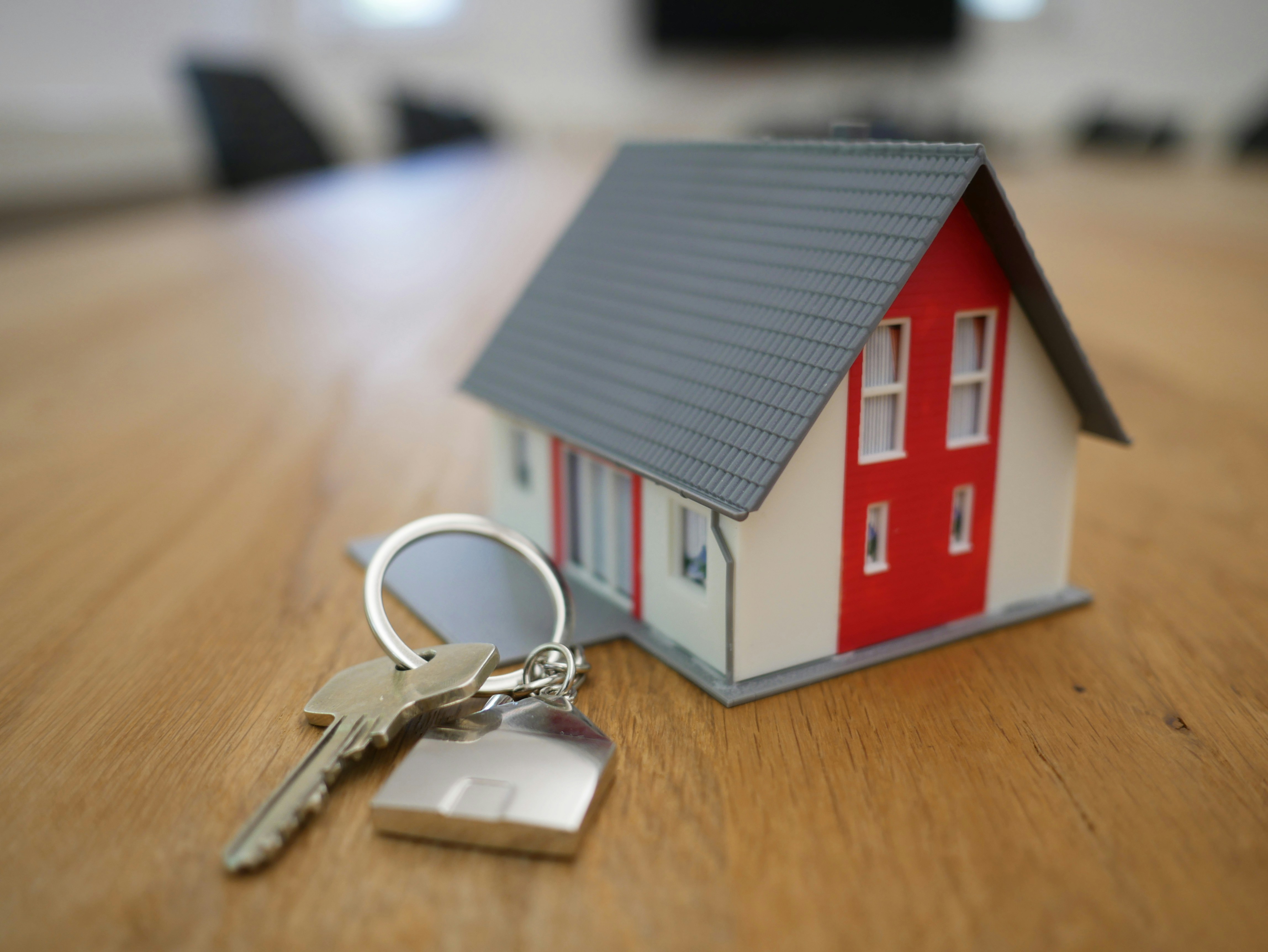 House keys on wooden table with miniature house model