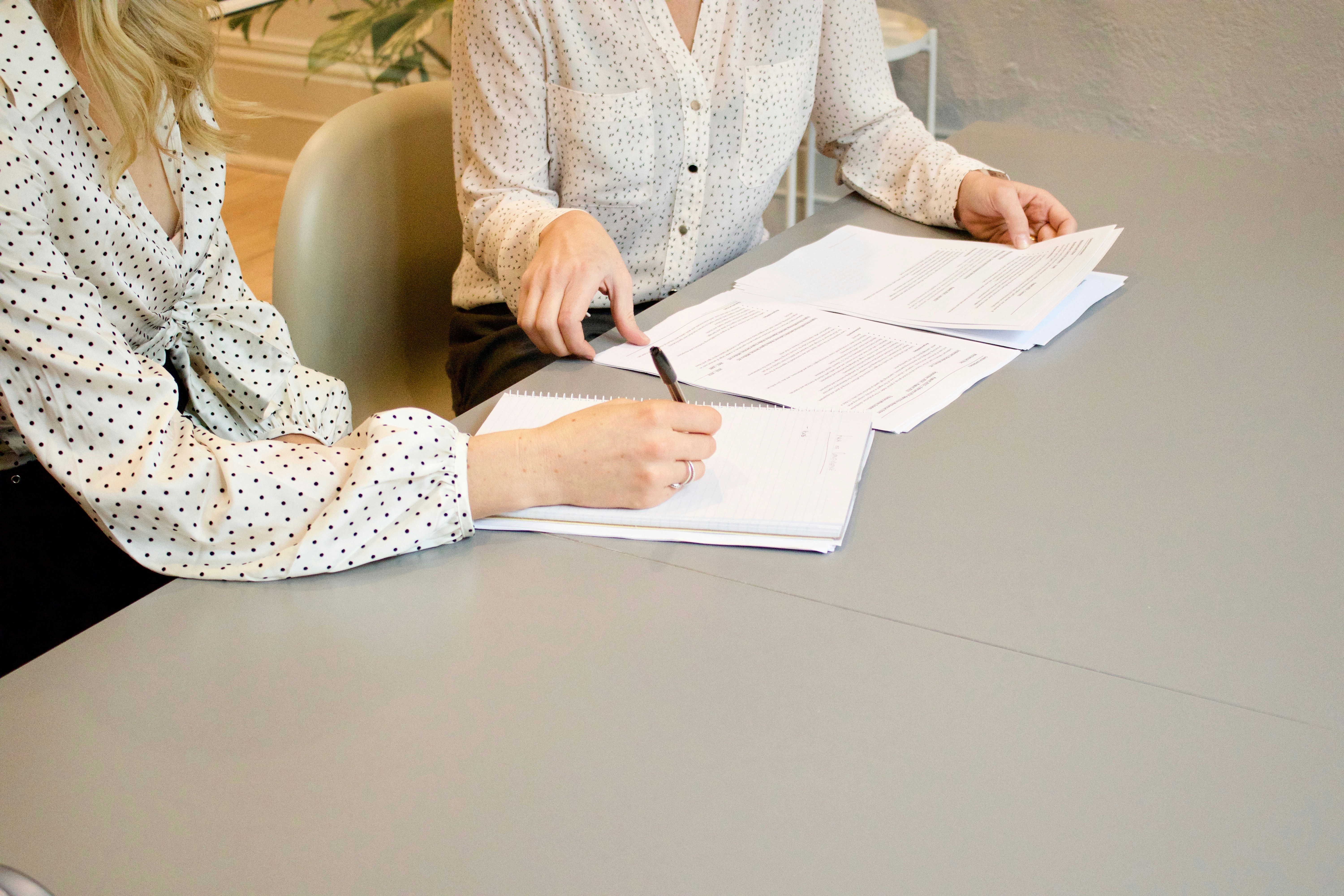 Two women signing documents at table